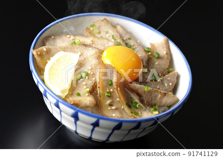 Hot pork bowl with cut lemon and egg yolk, grilled meat bowl shot on a black background Hot pork bowl with cut lemon and egg yolk, grilled meat bowl shot on a black background 91741129