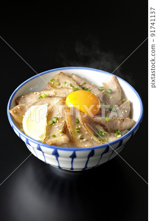 Hot pork bowl with cut lemon and egg yolk, grilled meat bowl shot on a black background Hot pork bowl with cut lemon and egg yolk, grilled meat bowl shot on a black background 91741137
