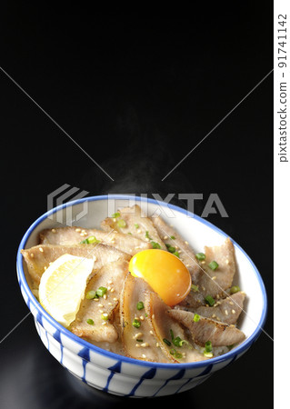 Hot pork bowl with cut lemon and egg yolk, grilled meat bowl shot on a black background Hot pork bowl with cut lemon and egg yolk, grilled meat bowl shot on a black background 91741142