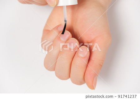 Applying a transparent varnish, degreaser to the nails close-up on a white background. Applying a transparent varnish, degreaser to the nails close-up on a white background. 91741237