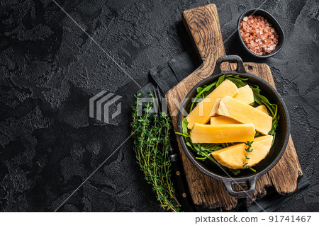 Halloumi cheese in pan ready for grilling. Black background. Top view. Copy space 91741467