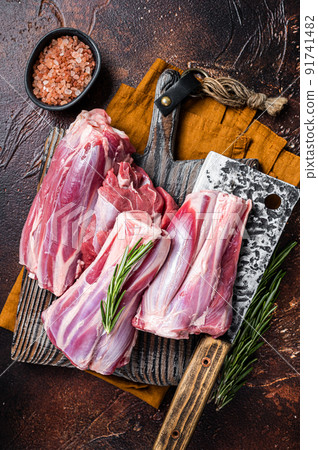 Uncooked Raw lamb mutton shanks on a butcher board. Dark background. Top view 91741482