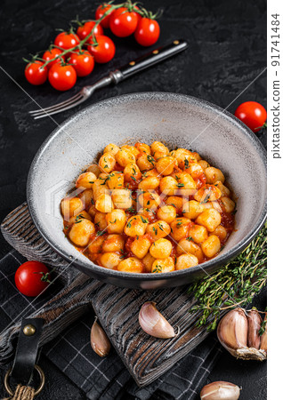 Gnocchi potato pasta with tomato sauce and thyme. Black background. Top view 91741484