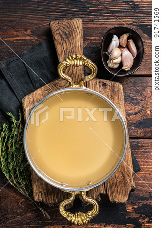 Clear broth stock without meat in cooking skillet. Wooden background. Top view 91741569