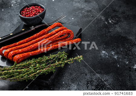 Smoked kabanos sausages with herbs on marble board. Black background. Top view. Copy space 91741683