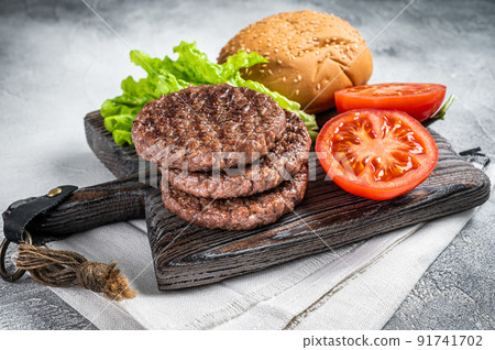 Fried cutlet for burger with vegetables and spices on wooden board. White background. Top view Fried cutlet for burger with vegetables and spices on wooden board. White background. Top view 91741702