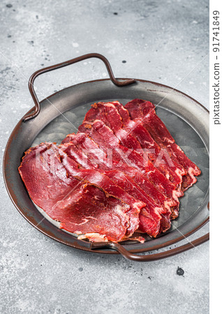 Sliced basturma, cured beef meat in steel tray. Gray background. Top view Sliced basturma, cured beef meat in steel tray. Gray background. Top view 91741849