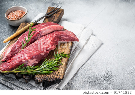 Butcher choise Bavette raw beef meat steak or flank flap on a wooden board with herbs. White background. Top view. Copy space 91741852