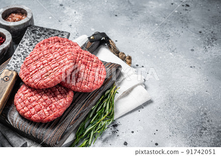 Raw beef meat burger patties on butcher wooden board with meat cleaver. Gray background. Top view. Copy space 91742051