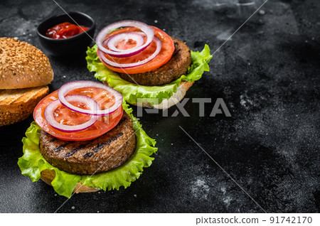 Vegan burger with Plant based meatless cutlets, patties, tomato and onion. Black background. Top view. Copy space Vegan burger with Plant based meatless cutlets, patties, tomato and onion. Black background. Top view. Copy space 91742170