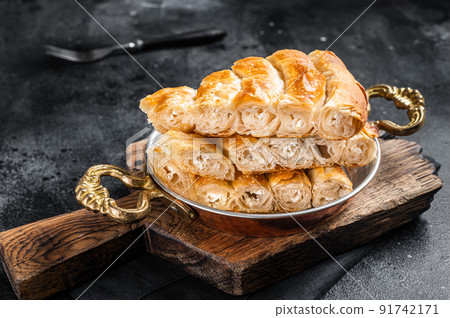 Traditional feta cheese phyllo pastry pie in rustic skillet. Black background. Top view Traditional feta cheese phyllo pastry pie in rustic skillet. Black background. Top view 91742171