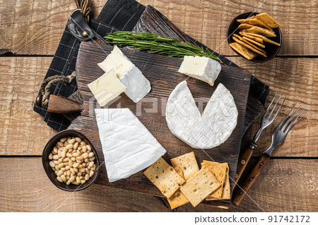 French cheese brie and camembert on wooden board with bread and nuts. Dairy products. Wooden background. Top view 91742172