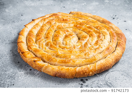 Baked homemade traditional Greek cheese pie on kitchen table. Gray background. Top view Baked homemade traditional Greek cheese pie on kitchen table. Gray background. Top view 91742173