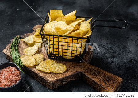 Potato chips with sea salt and rosemary in a basket. Dark background. Top view 91742182
