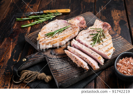 BBQ grilled pork chop steaks or cutlets sliced on wooden cutting board. Wooden background. Top view BBQ grilled pork chop steaks or cutlets sliced on wooden cutting board. Wooden background. Top view 91742219