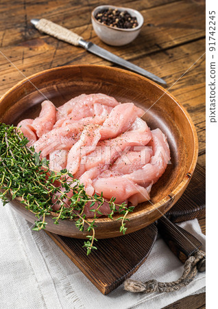 Sliced raw chicken, turkey breast meat in a wooden plate with thyme. Wooden background. Top view 91742245