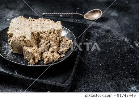 Homemade sunflower halva with honey. Black background. Top view. Copy space Homemade sunflower halva with honey. Black background. Top view. Copy space 91742449