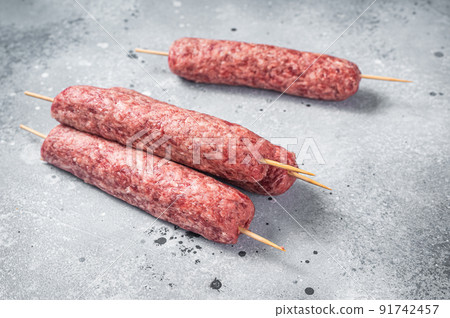 Raw kofta or lula kebabs skewers on butcher board. Gray background. Top view Raw kofta or lula kebabs skewers on butcher board. Gray background. Top view 91742457