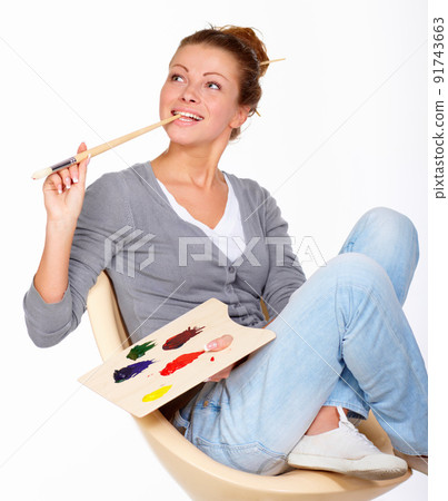 The inspiration is somewhere around here.... Studio shot of a young woman holding a palette and brush looking for inspiration. 91743663