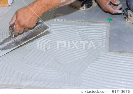 Applying wet mortar to the floor of the bathroom before applying tiles makes adhesive Applying wet mortar to the floor of the bathroom before applying tiles makes adhesive 91743676