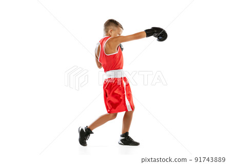 Portrait of active boy, beginner boxer in sports gloves and red uniform isolated on white background. Concept of sport, movement, studying, achievements, lifestyle. Portrait of active boy, beginner boxer in sports gloves and red uniform isolated on white background. Concept of sport, movement, studying, achievements, lifestyle. 91743889