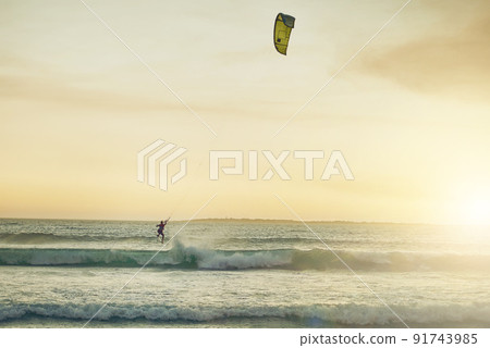 Catching some waves. Rearview shot of a young woman kitesurfing at the beach. Catching some waves. Rearview shot of a young woman kitesurfing at the beach. 91743985