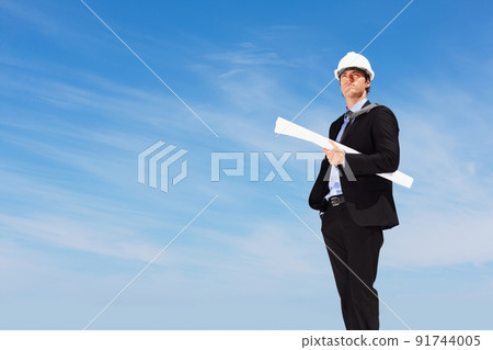 An architect with blueprints standing against clear sky. Business blueprint - An architect with papers standing against clear sky. 91744005
