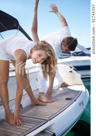 Doing their morning exercises. Young couple exercising together on a yacht. 91744397