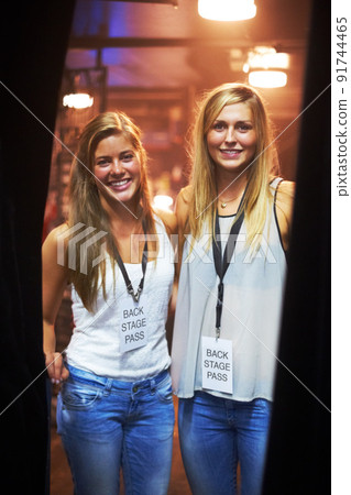 Two young women with backstage passes at a concert. This concert was created for the sole purpose of this photo shoot, featuring 300 models and 3 live bands. All people in this shoot are model 91744465