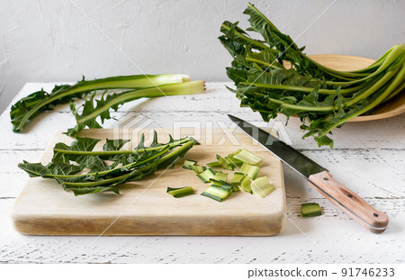 Chicory greens cut on wooden cutting board. knife, bounces aside. White wooden background 91746233
