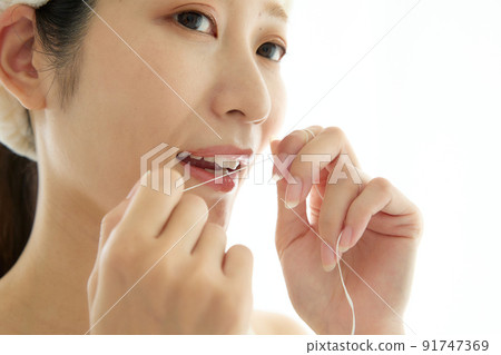 A woman doing dental floss in the bathroom A woman doing dental floss in the bathroom 91747369