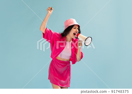 Portrait of beautiful young girl in pink panama posing isolated over light blue studio background. Emotive fan 91748375