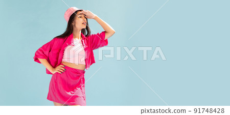 Portrait of beautiful young girl in pink panama posing, looking away isolated over light blue studio background. Flyer 91748428