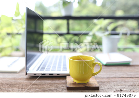Yellow coffee cup an laptop side view 91749879