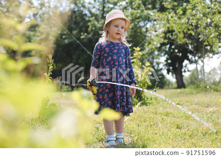 Adorable little girl playing with a garden hose on hot and sunny summer day Adorable little girl playing with a garden hose on hot and sunny summer day 91751596