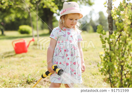 Adorable little girl playing with a garden hose on hot and sunny summer day Adorable little girl playing with a garden hose on hot and sunny summer day 91751599