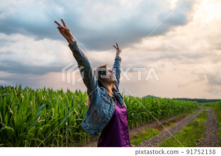 Young woman celebrating life standing in nature with raised arms Young woman celebrating life standing in nature with raised arms 91752138