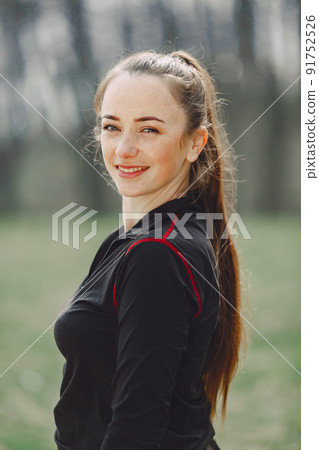 Woman in a black sportswear. Girl in a spring park. 91752526