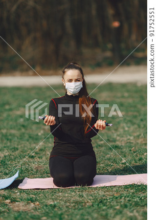 Beautiful girl training. Girl in a summer park. Lady make a yoga. Coronavirus theme 91752551