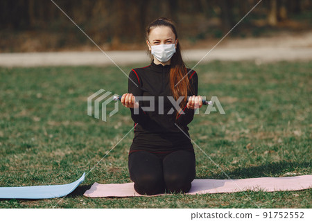 Beautiful girl training. Girl in a summer park. Lady make a yoga. Coronavirus theme Beautiful girl training. Girl in a summer park. Lady make a yoga. Coronavirus theme 91752552