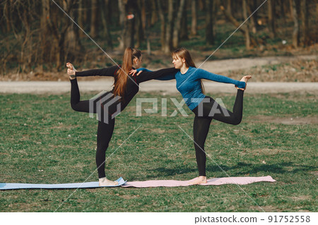 Beautiful girls training. Women in a summer park. Ladies make a yoga 91752558