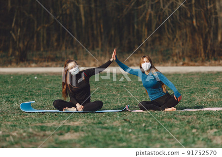 Beautiful girls training. Girls in a summer park. Lady make a yoga. Coronavirus theme 91752570