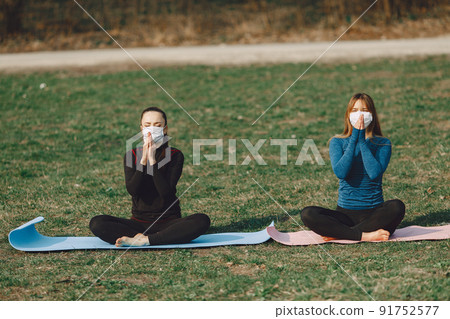 Beautiful girls training. Girls in a summer park. Lady make a yoga. Coronavirus theme 91752577