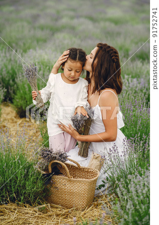 Mother with little daughter on lavender background. Beautiful woman and cute baby playing in meadow field. Family holiday in summer day. 91752741