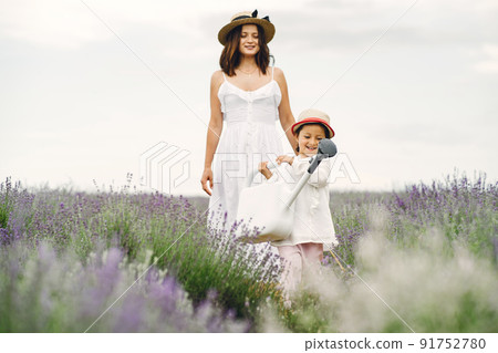 Mother with little daughter on lavender background. Beautiful woman and cute baby playing in meadow field. Family holiday in summer day. Mother with little daughter on lavender background. Beautiful woman and cute baby playing in meadow field. Family holiday in summer day. 91752780