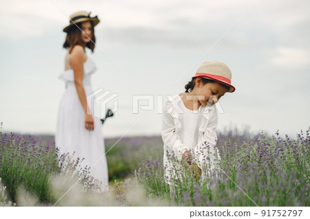 Mother with little daughter on lavender background. Beautiful woman and cute baby playing in meadow field. Family holiday in summer day. 91752797