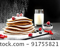 Large American pancakes on a dark background. Breakfast European. Chef sprinkles pancakes with powdered sugar on black background. Food for breakfast healthy eating. Pancakes with honey. Homemade 91755821