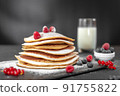 Serving pancakes with powdered sugar and berries. Chef man hand. Beautiful food still life. Natural light, slightly toned image, dark black background with text area. Horizontal view 91755822