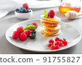 Mini pancakes with honey and berries. An American traditional breakfast. Breakfast for the whole family. Healthy Eating. Honey poured over the pancakes. Food for breakfast healthy eating. Pancakes 91755827