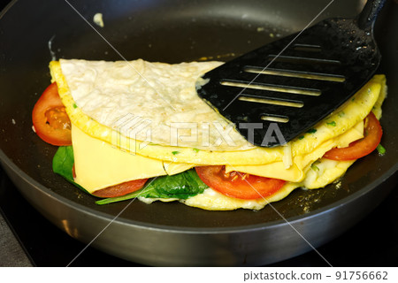 Pita wrap with tomatoes, cheese, ham and spinach on the frying pan Pita wrap with tomatoes, cheese, ham and spinach on the frying pan 91756662